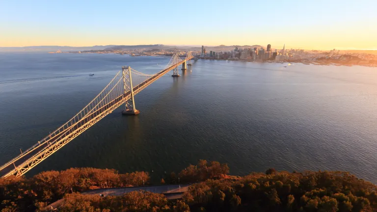 The West Span of the Bay Bridge stretches from Yerba Buena Island in the foreground to San Francisco in the background as the sun rises.