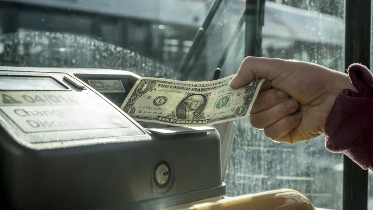 A person putting money into a bus fare box