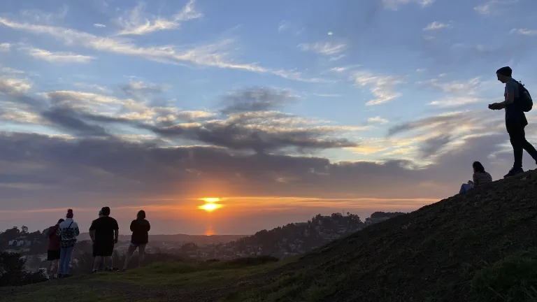 Silhouette of people atop San Francisco's Twin Peaks enjoying a beautiful sunset over the Pacific Ocean.