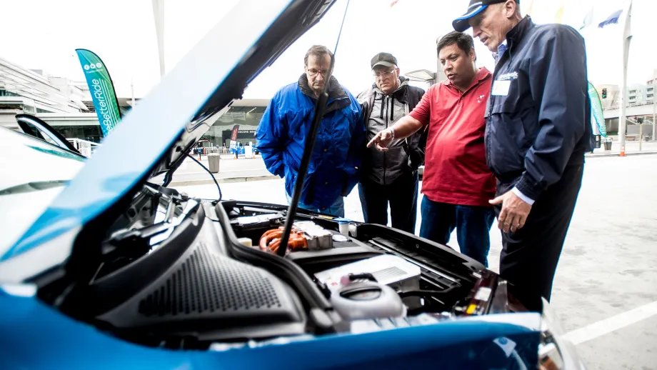 people looking under the hood of electric car