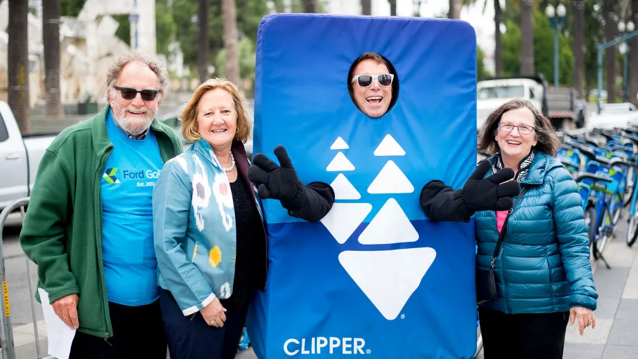 3 people posing for a picture with clipper card mascot