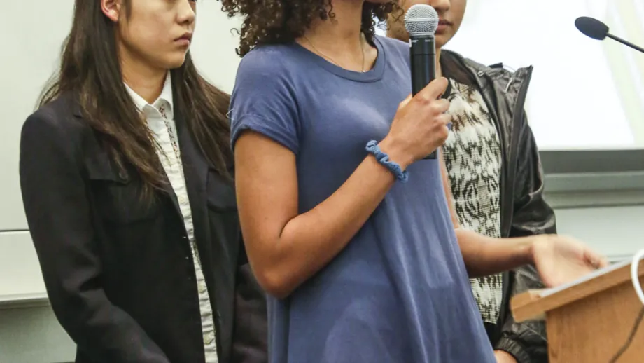 young adult holding microphone next to a podium