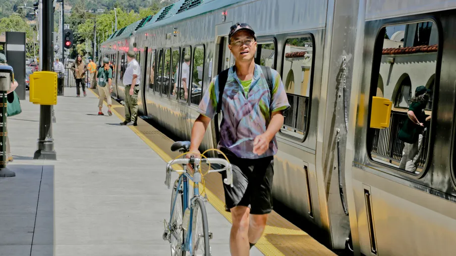 man walking bike next to train