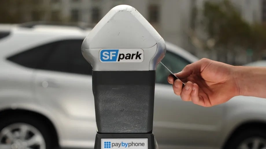 A driver inserts a credit card in a smart parking meter in SF.